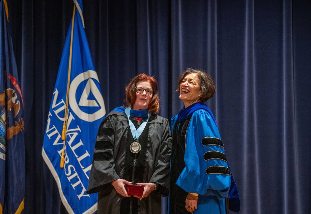 Provost Mili laughs next to woman on stage